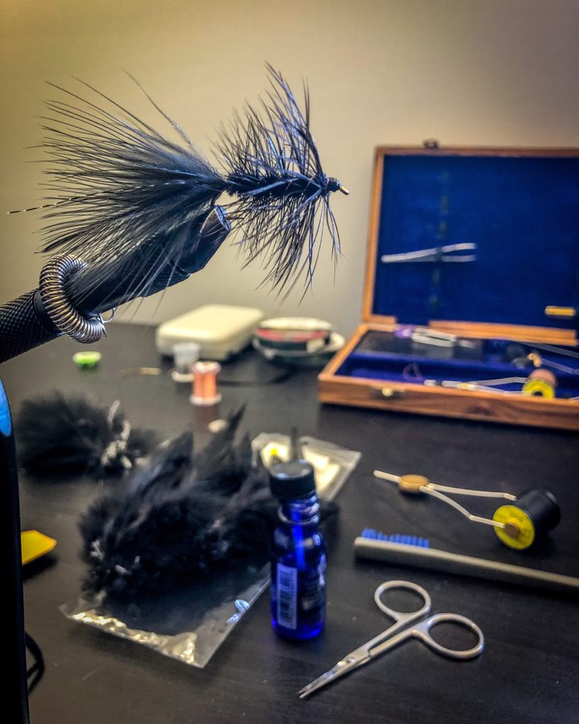 Finished black woolly bugger in the tying vice.